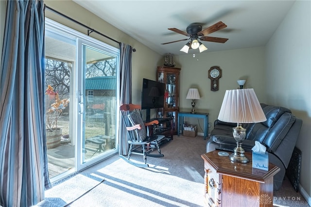 carpeted living room with ceiling fan and baseboards