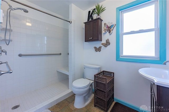 bathroom featuring a sink, toilet, and a tile shower