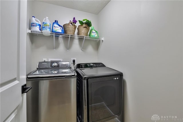 washroom featuring a textured ceiling, washing machine and dryer, and laundry area