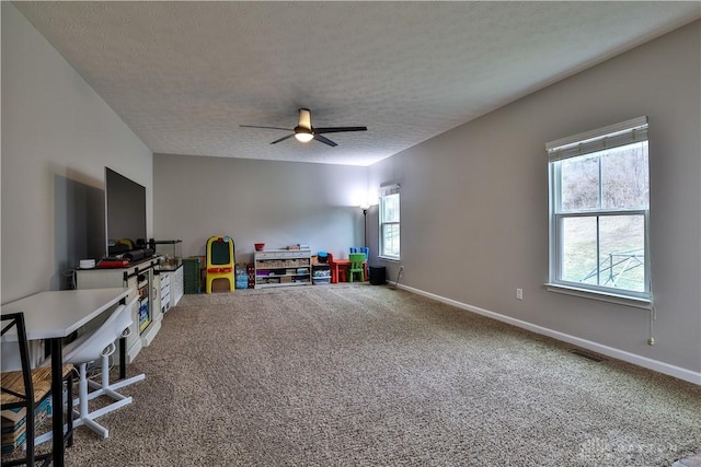 playroom with baseboards, a textured ceiling, ceiling fan, and carpet