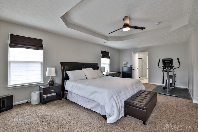 bedroom featuring baseboards, a raised ceiling, and a textured ceiling