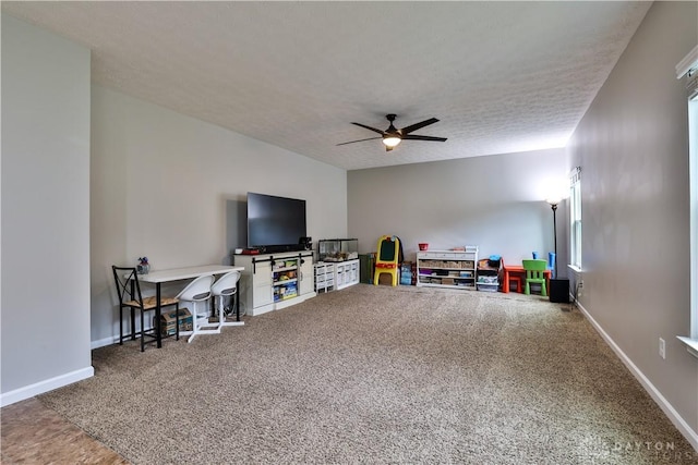 playroom featuring carpet flooring, a ceiling fan, baseboards, and a textured ceiling