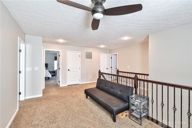 sitting room featuring visible vents, a textured ceiling, baseboards, and carpet floors