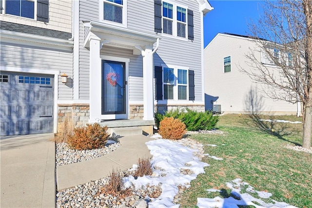 entrance to property with stone siding, a lawn, central air condition unit, and a garage