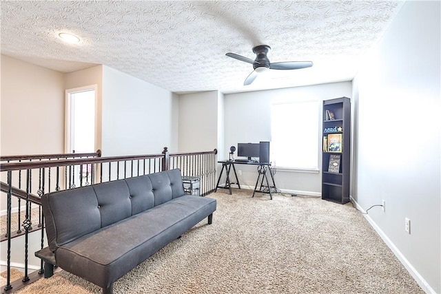 living area with a textured ceiling, baseboards, carpet, and a ceiling fan