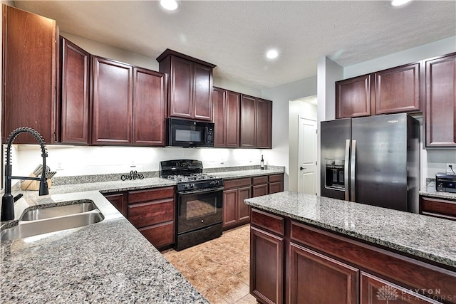 kitchen with light stone counters, recessed lighting, black appliances, and a sink