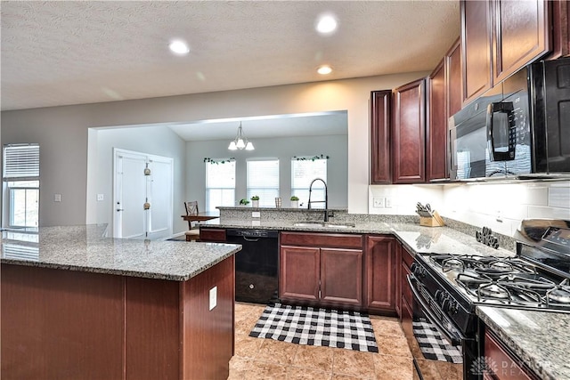 kitchen featuring black appliances, light stone counters, and a sink