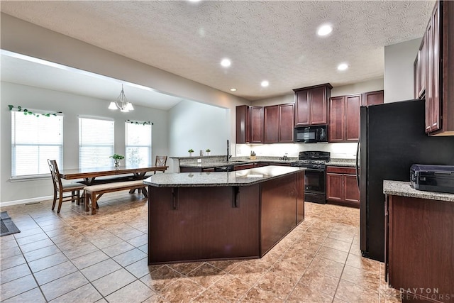 kitchen featuring black appliances, light tile patterned floors, stone counters, and a kitchen island