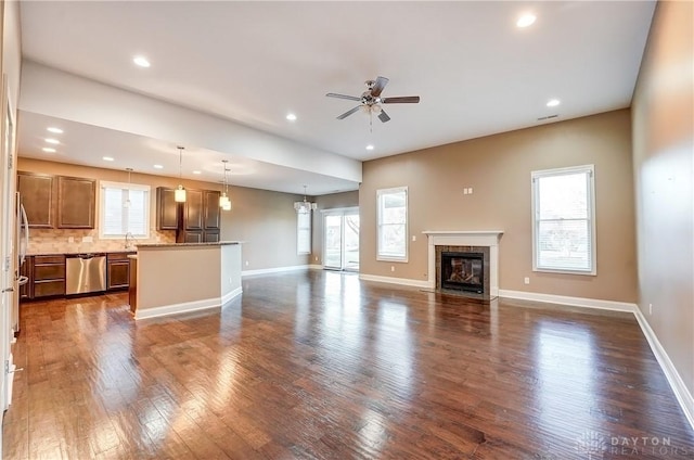 unfurnished living room with dark wood finished floors, a fireplace with flush hearth, and a wealth of natural light