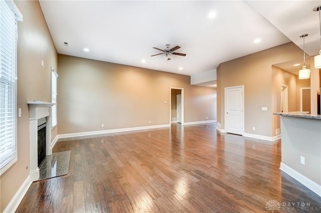 unfurnished living room with baseboards, ceiling fan, recessed lighting, a fireplace, and wood finished floors