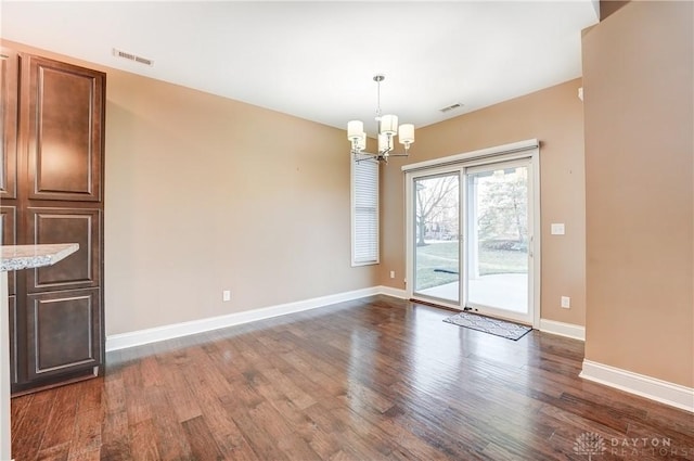 unfurnished dining area with dark wood finished floors, a notable chandelier, baseboards, and visible vents