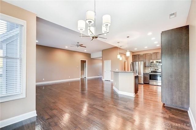 unfurnished living room with visible vents, ceiling fan with notable chandelier, wood finished floors, recessed lighting, and baseboards