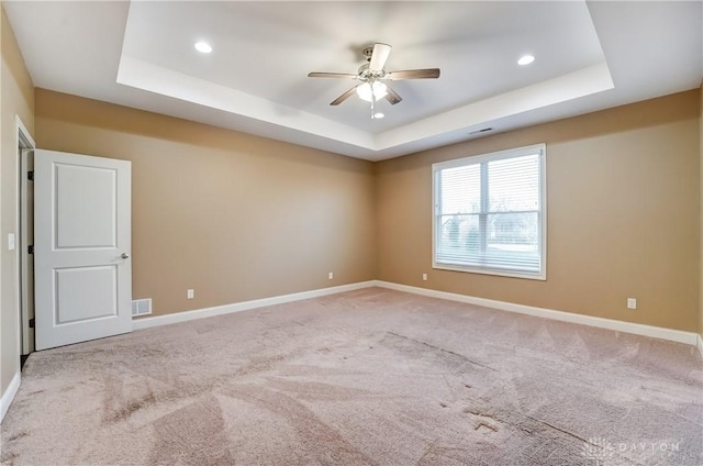 unfurnished room featuring a raised ceiling, baseboards, and light carpet