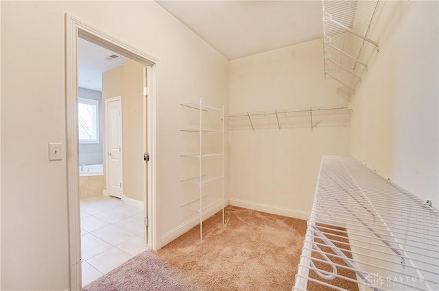 spacious closet with visible vents, carpet floors, and tile patterned flooring