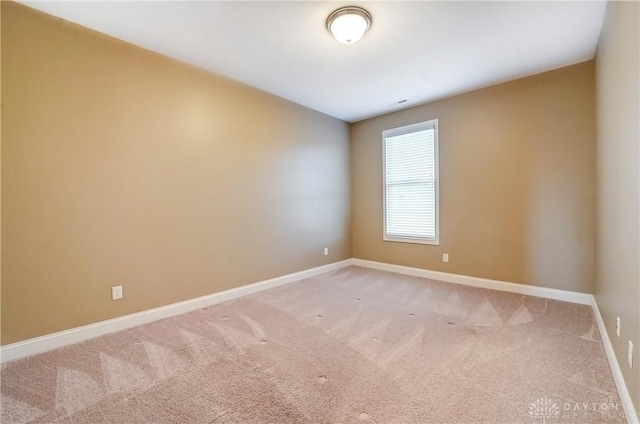 spare room featuring baseboards and light carpet