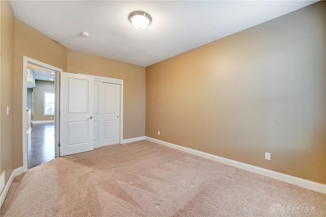 unfurnished bedroom featuring a closet, baseboards, and light colored carpet