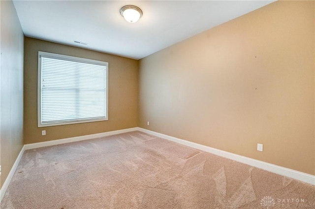 empty room featuring visible vents, baseboards, and light colored carpet