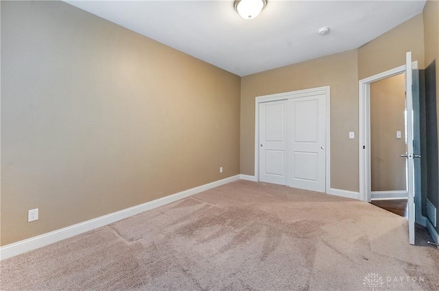 unfurnished bedroom with a closet, baseboards, and carpet floors