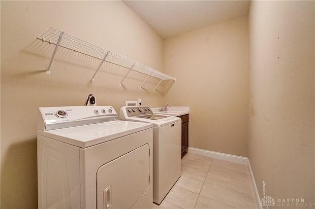 laundry area with washer and clothes dryer, a sink, cabinet space, light tile patterned floors, and baseboards