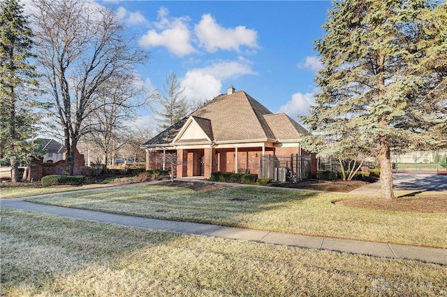 view of front facade featuring fence, a shingled roof, a chimney, a front lawn, and brick siding