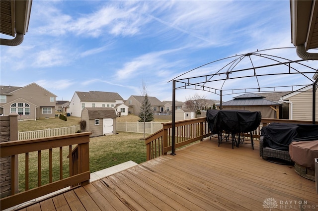 wooden deck featuring an outbuilding, a shed, a fenced backyard, a lawn, and a residential view