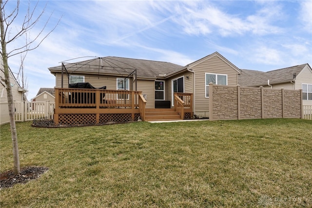 back of property featuring a deck, a lawn, and a fenced backyard