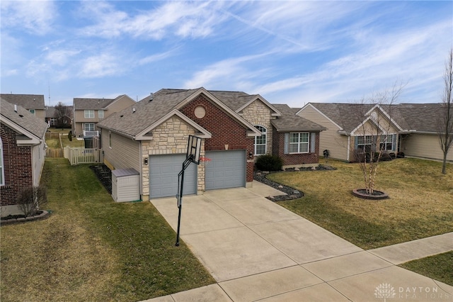 view of front of house featuring a front yard, fence, driveway, a shingled roof, and stone siding