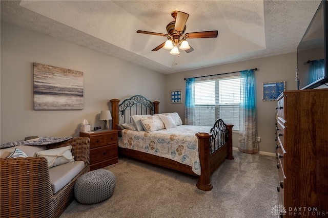 bedroom with a raised ceiling, light carpet, baseboards, and a textured ceiling