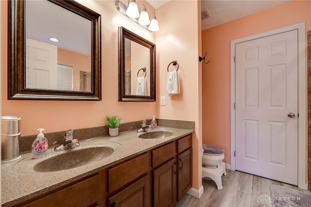 bathroom with double vanity, toilet, visible vents, and a sink