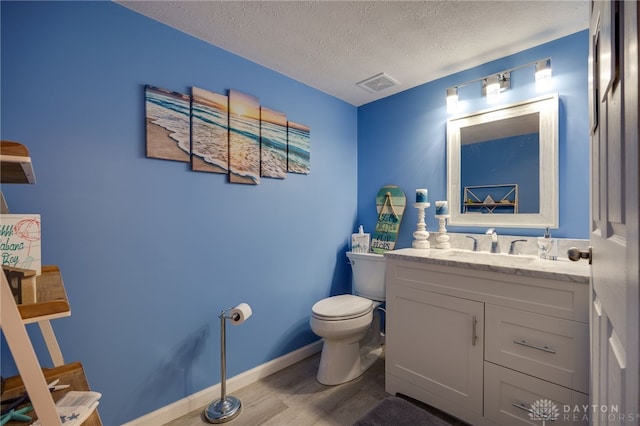 half bath featuring visible vents, toilet, a textured ceiling, wood finished floors, and vanity