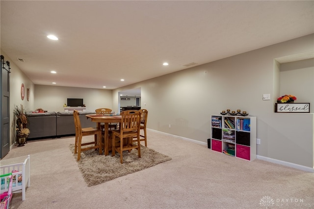 dining space featuring recessed lighting, a barn door, light carpet, and baseboards