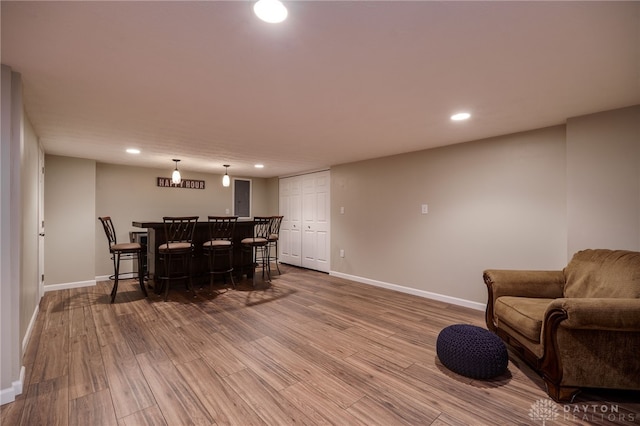 interior space featuring recessed lighting, baseboards, a bar, and wood finished floors