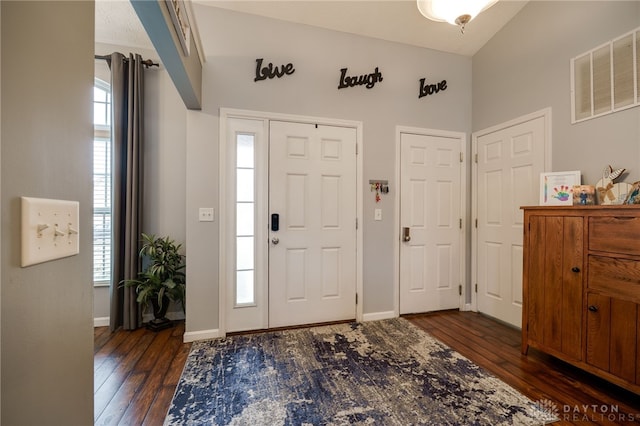 entrance foyer with visible vents, baseboards, dark wood-type flooring, and lofted ceiling