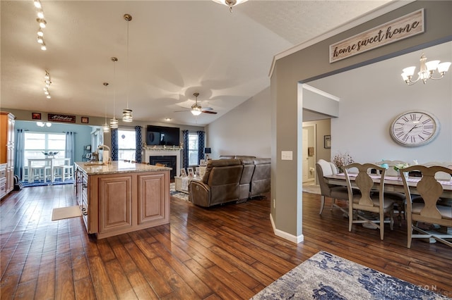 kitchen featuring dark wood finished floors, vaulted ceiling, light stone counters, and a fireplace