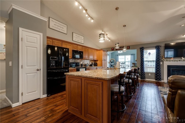 kitchen with brown cabinets, black appliances, a sink, open floor plan, and lofted ceiling