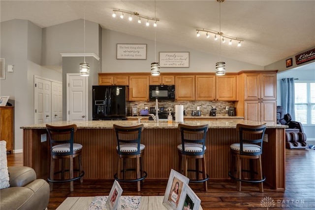 kitchen with a spacious island, dark wood-style floors, black appliances, and a kitchen bar