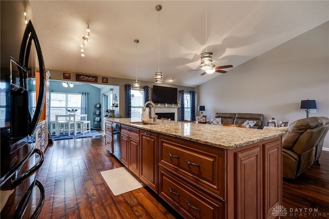 kitchen featuring dark wood-style floors, a fireplace, a sink, vaulted ceiling, and open floor plan