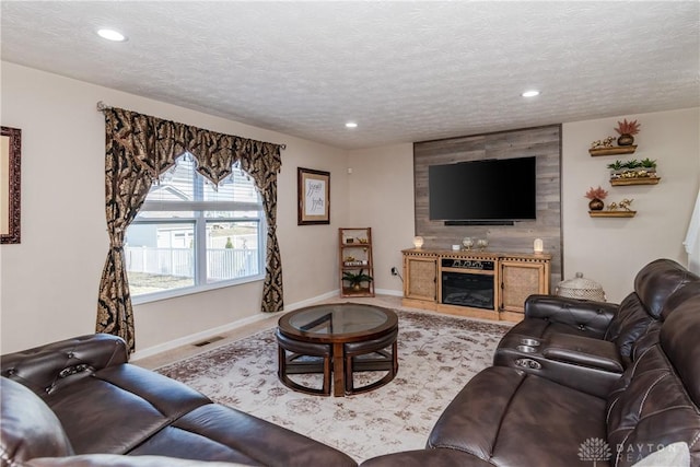 living area with recessed lighting, visible vents, baseboards, and a textured ceiling