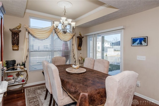 dining space featuring crown molding, baseboards, wood finished floors, a notable chandelier, and a raised ceiling