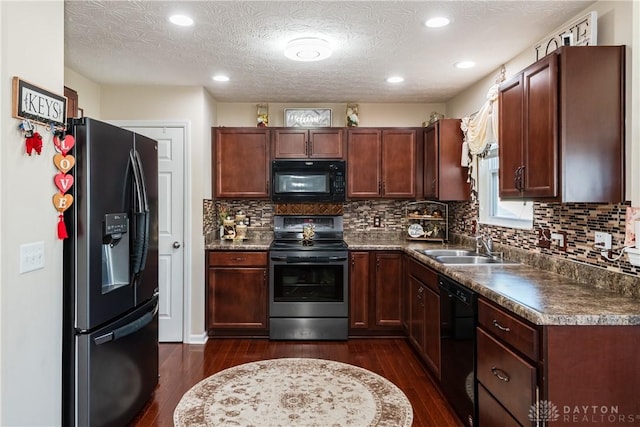 kitchen with black appliances, a sink, dark countertops, a textured ceiling, and dark wood-style flooring