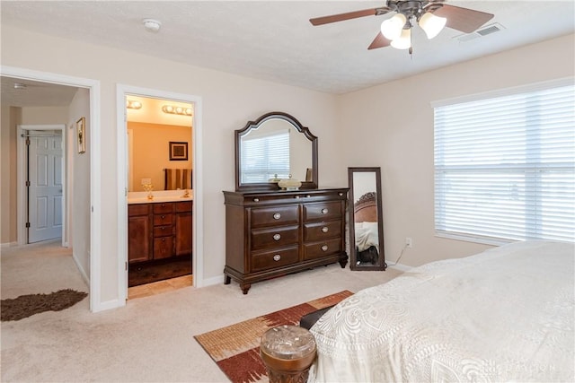 bedroom with baseboards, visible vents, ensuite bath, ceiling fan, and light carpet