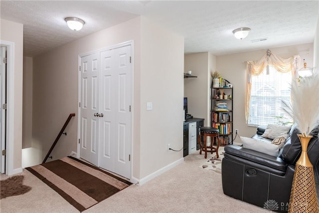 sitting room featuring visible vents, baseboards, a textured ceiling, light carpet, and an upstairs landing