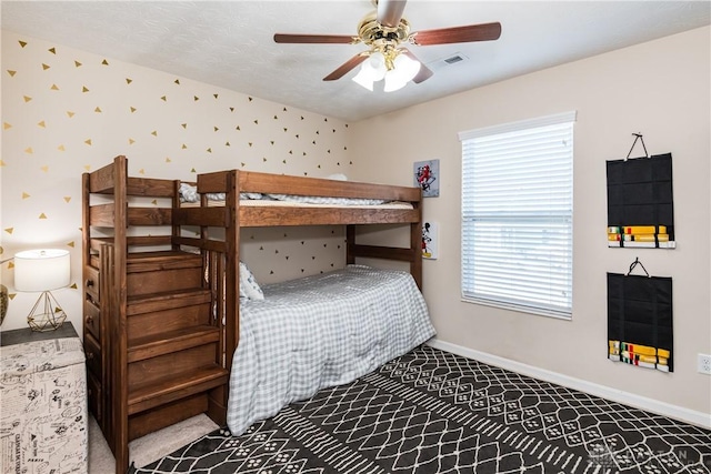 bedroom featuring wallpapered walls, a ceiling fan, baseboards, and a textured ceiling