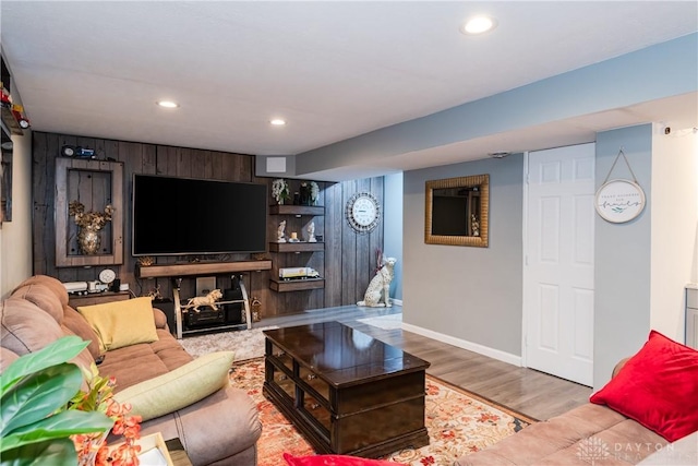 living room with recessed lighting, baseboards, wood finished floors, and wood walls