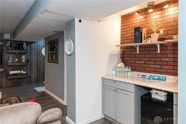 bar featuring baseboards, brick wall, and dark wood-style flooring