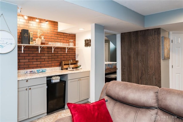 kitchen with fridge, brick wall, and a sink