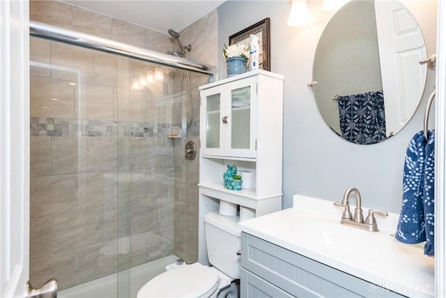 bathroom with vanity, a shower stall, and toilet