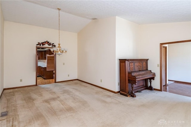 unfurnished room with baseboards, vaulted ceiling, carpet floors, an inviting chandelier, and a textured ceiling