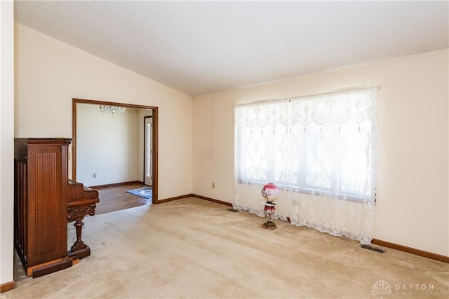 empty room featuring visible vents, carpet floors, baseboards, and vaulted ceiling