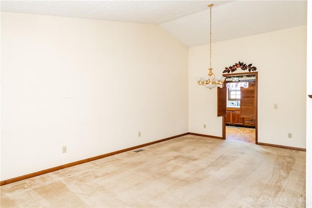 unfurnished room with baseboards, light carpet, a chandelier, and vaulted ceiling